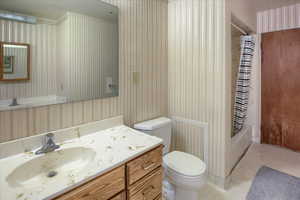 Full bathroom with toilet, shower / bath combination with curtain, tile patterned flooring, and vanity