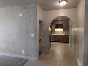 Corridor with arched walkways, light tile patterned floors, visible vents, and a sink