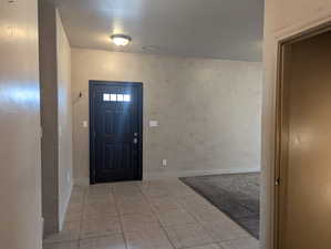 Foyer with tile patterned floors, visible vents, a textured ceiling, and baseboards