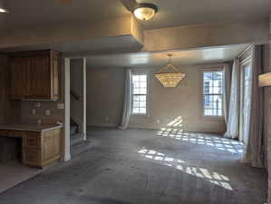 Interior space with baseboards, light colored carpet, and stairs