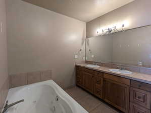 Full bathroom with a sink, tile patterned floors, double vanity, and a textured ceiling