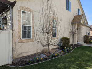 View of property exterior with stucco siding, fence, and a lawn