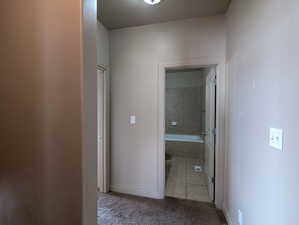 Hall featuring baseboards, a textured ceiling, and carpet floors