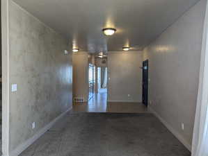 Hallway with tile patterned flooring, carpet, visible vents, and a textured ceiling