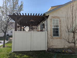 View of home's exterior with a pergola, stucco siding, and fence
