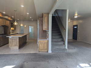 Kitchen featuring light tile patterned floors, a center island, baseboards, recessed lighting, and light carpet