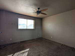 Carpeted spare room featuring a textured ceiling, baseboards, and ceiling fan