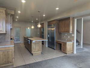 Kitchen featuring light colored carpet, an island with sink, built in appliances, and recessed lighting