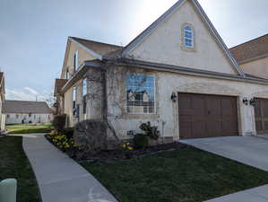 View of side of home featuring a yard, concrete driveway, and stucco siding