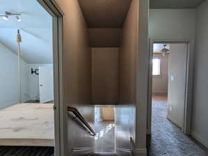 Interior space with a textured ceiling, baseboards, vaulted ceiling, and carpet floors
