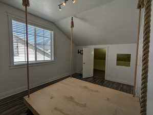 Bonus room featuring baseboards, a textured ceiling, wood finished floors, and lofted ceiling