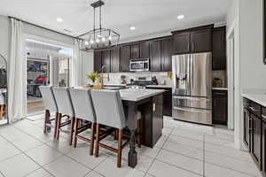 Kitchen with appliances with stainless steel finishes, sink, a breakfast bar, decorative light fixtures, and an island with sink