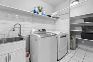 Clothes washing area featuring cabinets, sink, independent washer and dryer, light tile patterned floors, and a textured ceiling