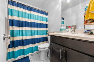 Bathroom with toilet, tile patterned floors, a shower with shower curtain, and vanity