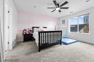 Bedroom featuring a textured ceiling, ceiling fan, and light colored carpet