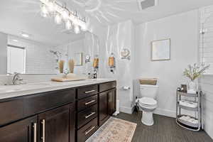 Bathroom featuring tiled shower, vanity, toilet, and tile patterned flooring