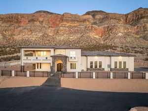 View of front facade with a fenced front yard, stone siding, a mountain view, and stucco siding