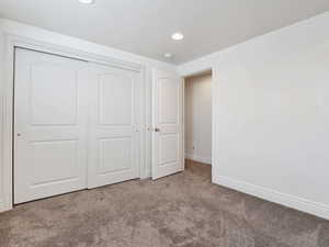 Unfurnished bedroom featuring light carpet and a closet