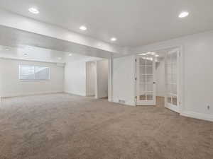 Basement with french doors and carpet flooring