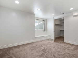 Unfurnished bedroom with a closet, a walk in closet, and carpet flooring