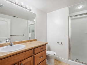 Bathroom with vanity, toilet, tile patterned floors, and walk in shower