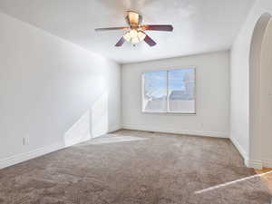 Carpeted empty room featuring ceiling fan and a textured ceiling