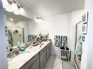 Bathroom featuring a textured ceiling, a shower with shower door, and vanity
