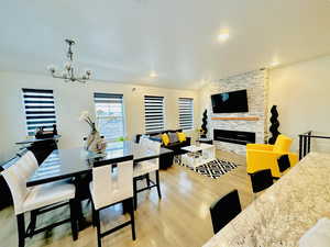 Dining space with light hardwood / wood-style floors, a chandelier, and a stone fireplace