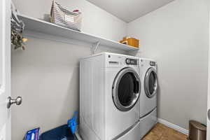 Clothes washing area featuring washer and dryer and tile patterned flooring