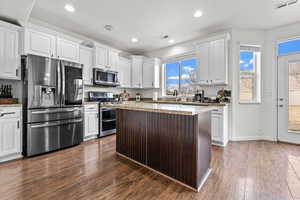 Kitchen featuring white cabinetry, stainless steel appliances, dark hardwood / wood-style flooring, a kitchen island, and light stone counters