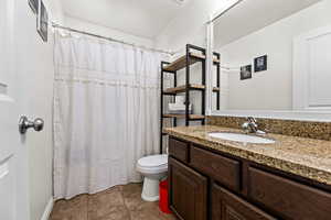 Bathroom with a shower with shower curtain, tile patterned flooring, vanity, and toilet