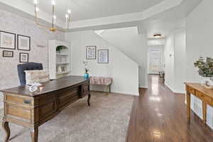 Office area with a raised ceiling and dark hardwood / wood-style flooring