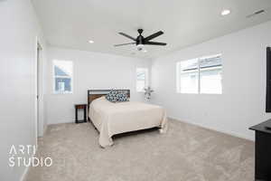 Carpeted bedroom with multiple windows and ceiling fan