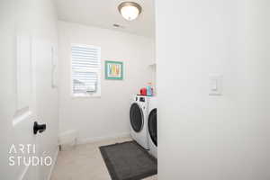 Laundry room with light tile patterned flooring and washer and dryer