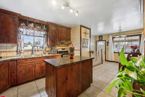 Kitchen with sink, a kitchen island, stainless steel range oven, and backsplash