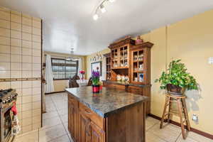 Kitchen with track lighting, light tile patterned floors, stainless steel range oven, and a center island