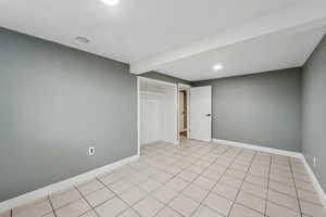 Spare room featuring beam ceiling and light tile patterned floors