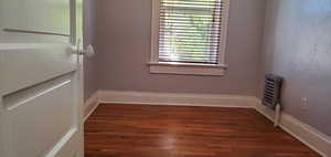 # 3 Unfurnished room featuring a textured wall and dark wood finished floors