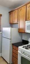 Unit # 3 Kitchen featuring white appliances, brown cabinets, dark stone countertops, and light tile patterned floors