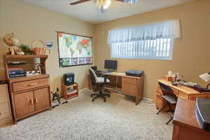 Carpeted home office featuring ceiling fan and a textured ceiling