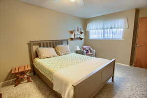 Bedroom featuring a textured ceiling, ceiling fan, and light colored carpet