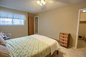 Carpeted bedroom with ceiling fan and a textured ceiling