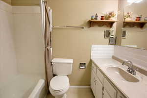 Full bathroom with vanity, toilet, tile patterned floors, and shower / bath combo with shower curtain