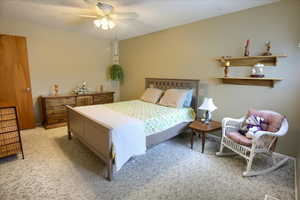 Carpeted bedroom with ceiling fan and a textured ceiling