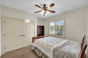 Bedroom featuring ceiling fan, light carpet, and a closet