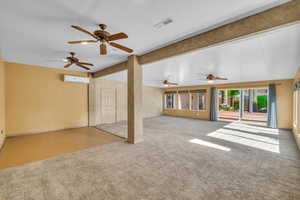 Unfurnished living room with visible vents, ceiling fan, an AC wall unit, and carpet floors