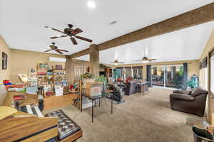 Carpeted living room featuring beam ceiling and a wall mounted air conditioner