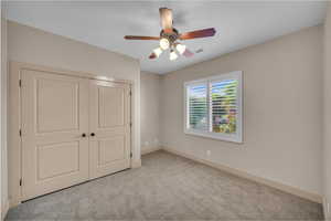 Unfurnished bedroom featuring a closet, ceiling fan, visible vents, baseboards, and carpet floors
