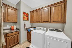 Washroom featuring washer and dryer, cabinets, sink, and light tile patterned flooring