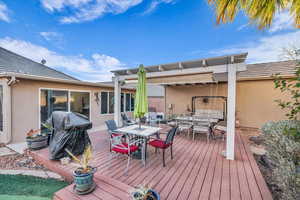 Wooden terrace featuring area for grilling and a pergola